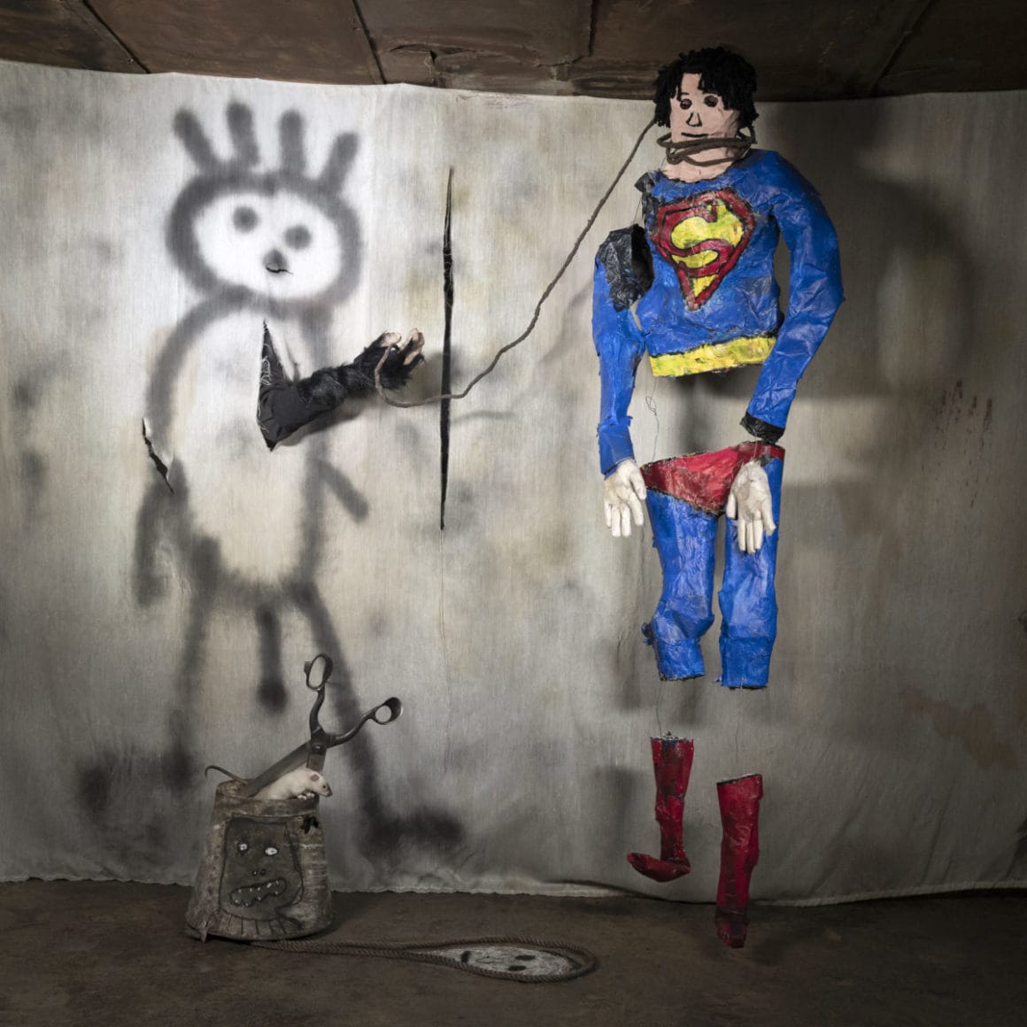 Roger Ballen, installation avec un superman désarticulé, une souris et plusieurs dessins. 