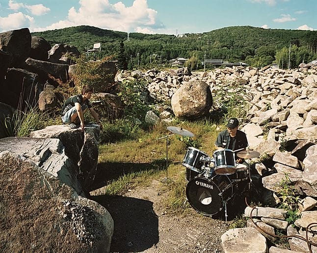 Yoshiki Hase, un batteur et sa batterie dans un champ de pierres. 