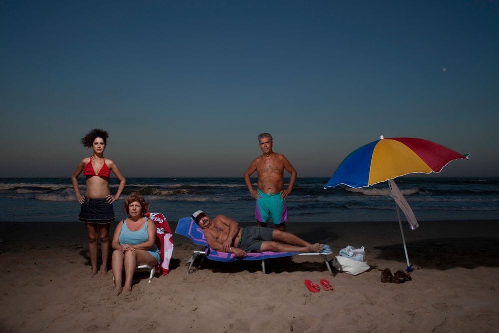 photographie issue de la série Tribes de l'artiste Lucía Herrero, mettant en scène quatre adultes, deux hommes et deux femmes à côté d'un parasol tricolore. 