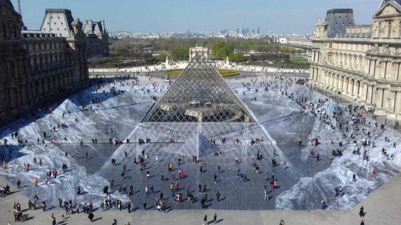 Collage de l'artiste JR devant la pyramide du Louvre 