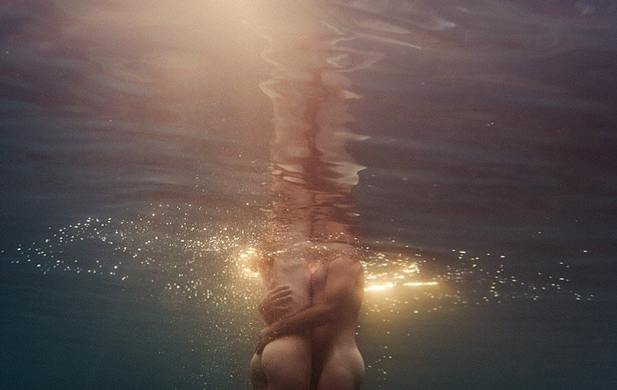 Photographie prise sous l'eau, un homme et une femme nus se serrent l'un contre l'autre