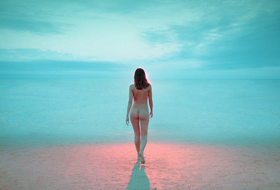 Une femme nue, de dos, 'avance vers la mer et vers une lumière rose