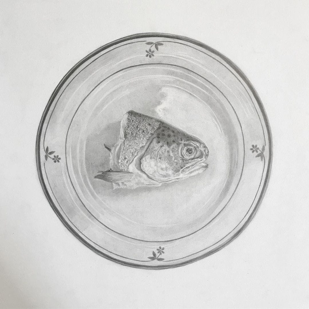 Une tête de poisson est posée au milieu d'une assiette à fleurs