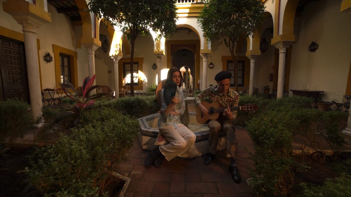 Jardin intérieur, un homme joue de la guitare et une femme s'évente avec un chapeau