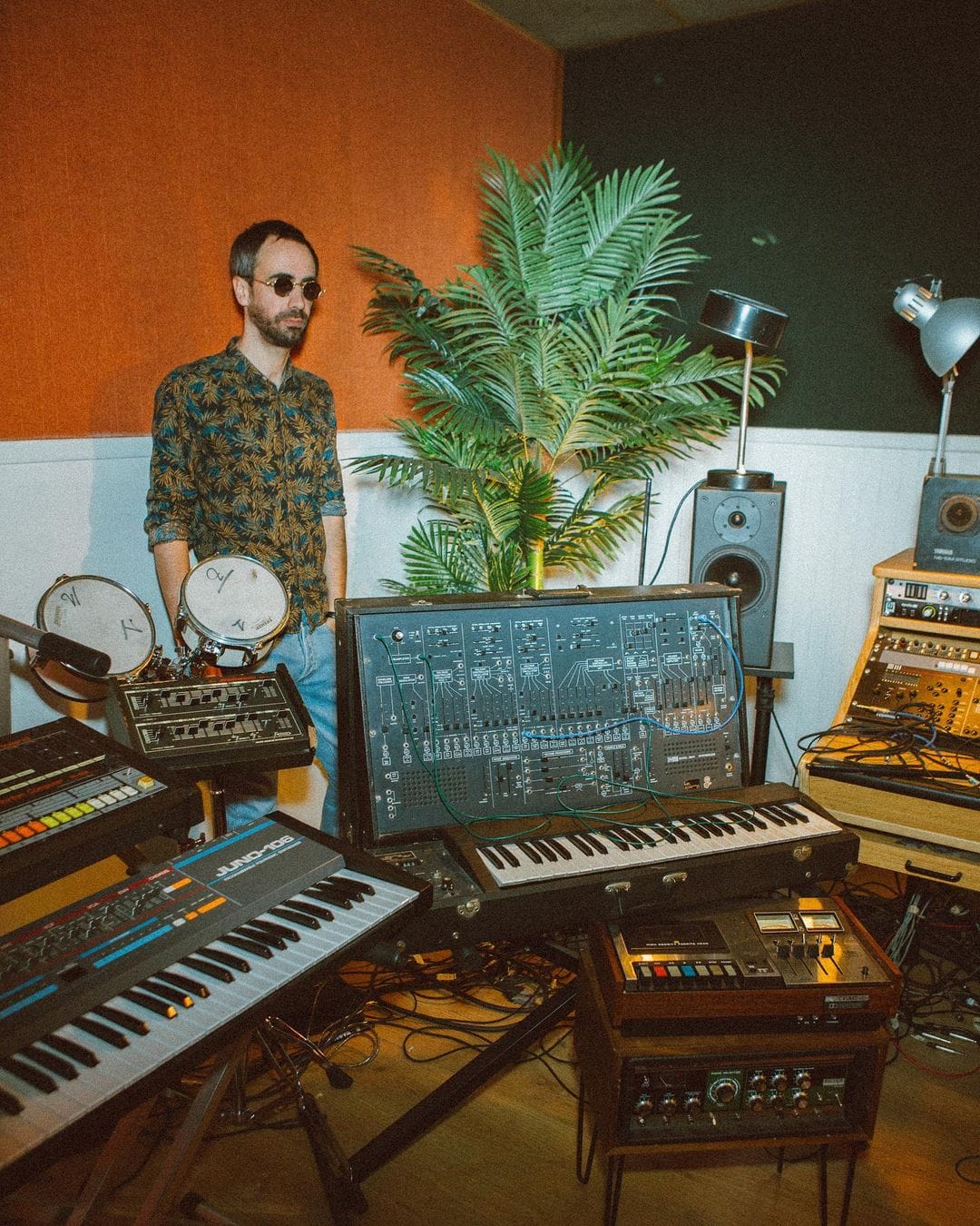 Image taser du projet Spectre, dont le premier volet est le titre Shin Sekai. Le DJ Para One dans son studio d'enregistrement, en chemise imprimée et lunettes de soleil. A côté de lui, un palmier et des murs orange et vert. 