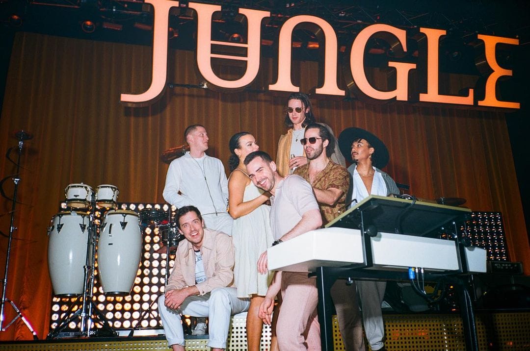 Les 7 membres du collectif Jungle destiné au live sourient sur scène, avant de commencer un concert.