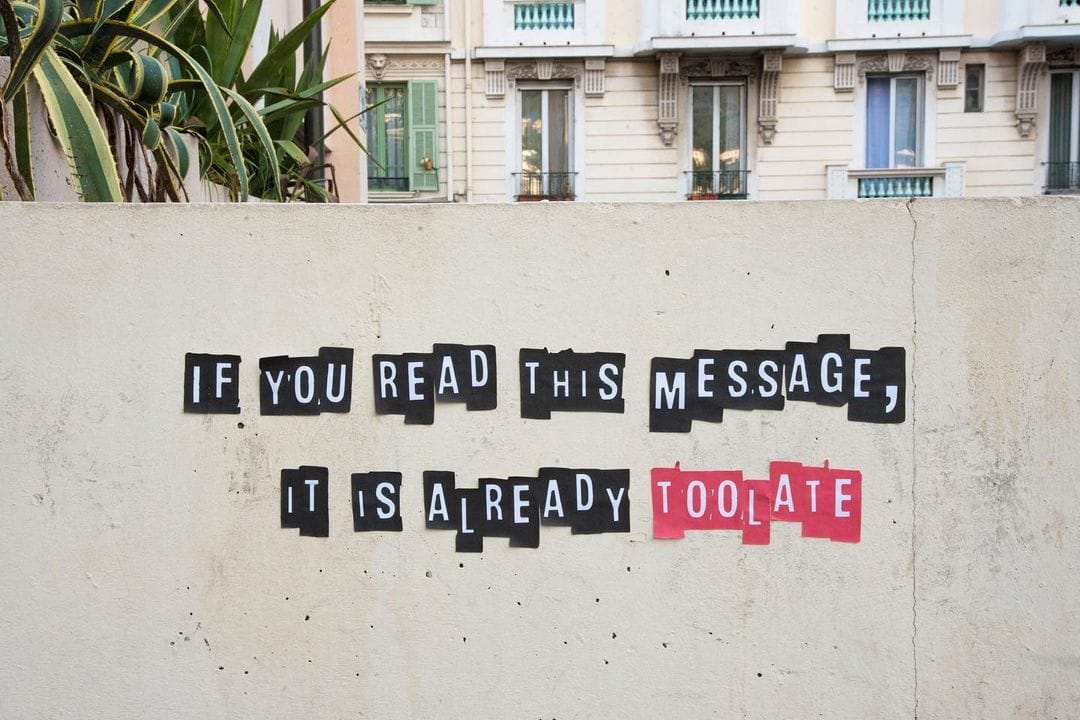 Pan de mur. Graffes de lettres encadrées d'un fond noir, "If you read this messages, it is already" et en rouge "too late".