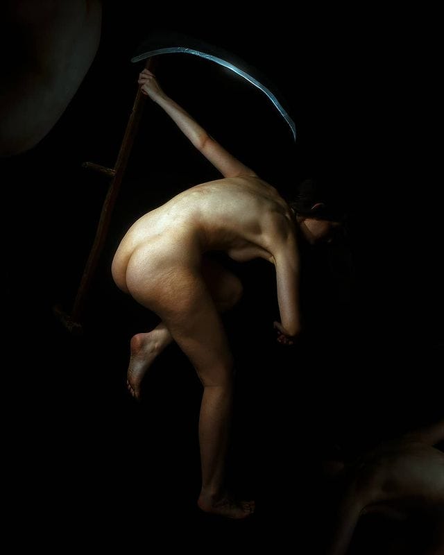 Photographie d'une femme nue tenant une fourche.