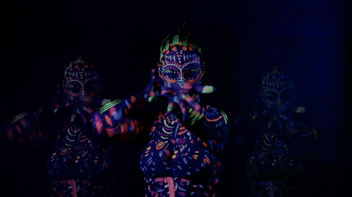 Extrait du clip "I AM THE GHOST", LIA MOON danse dans le noir, couverte de peinture fluorescente. Effet de multiplication des figures psychédélique.