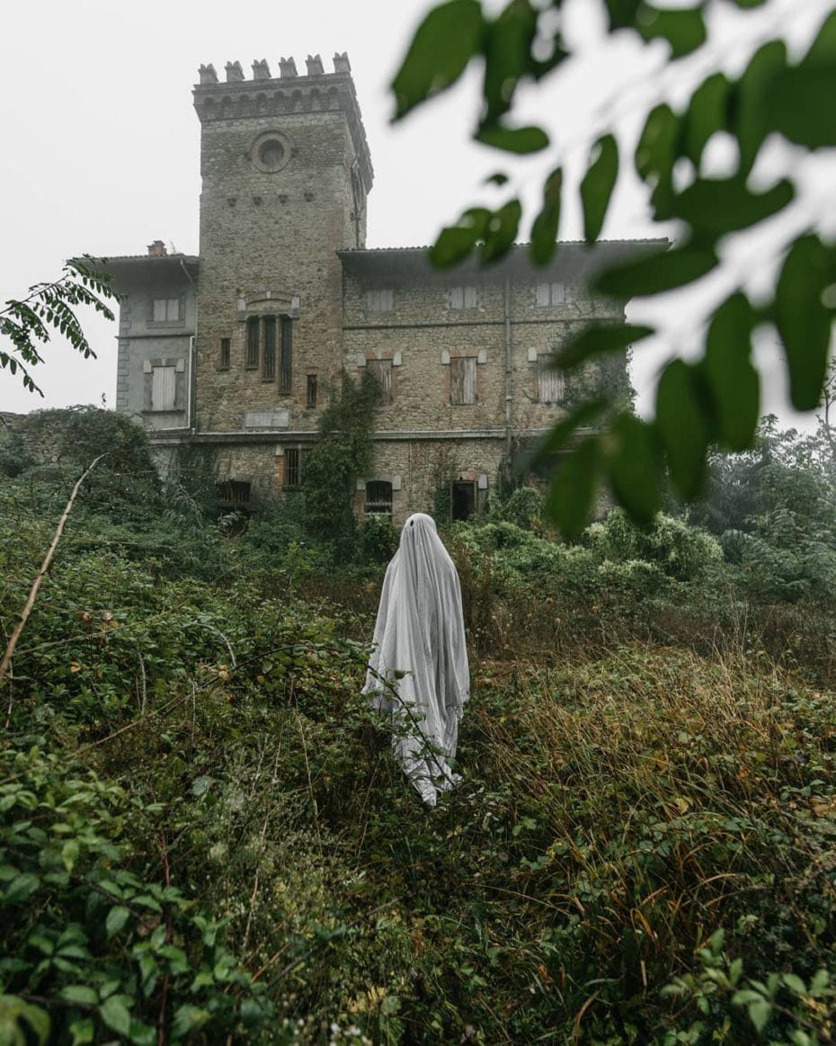 Devant une énorme maison abandonnée, le fantôme drapé regarde à sa droite