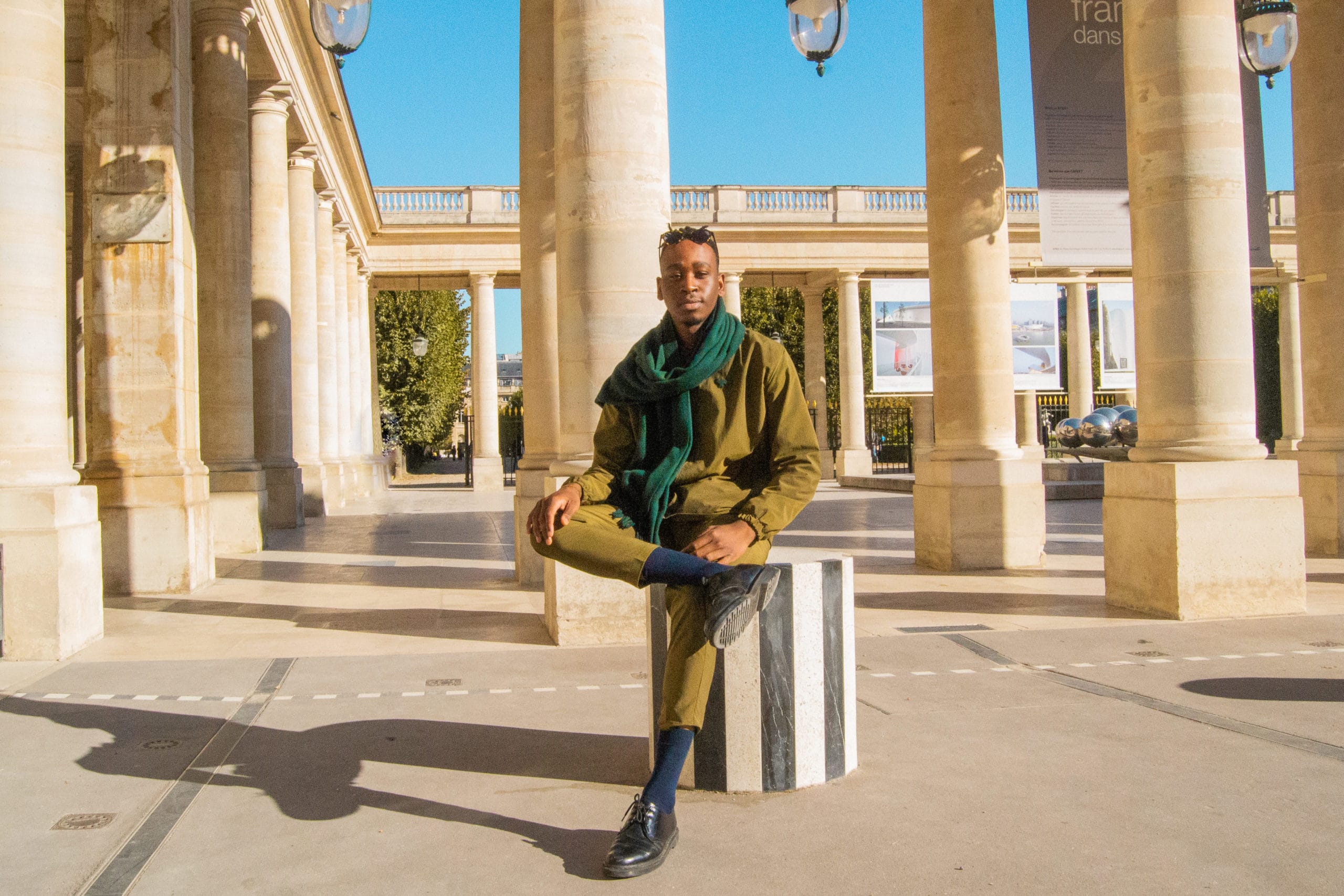 L'artiste Khazali est assis sur une des colonnes de Buren, dans la cour du Palais Royal.