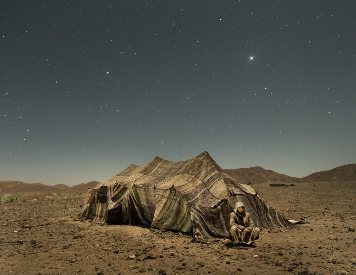 Photographie d'une tente au milieu du désert sous un ciel étoilé.
