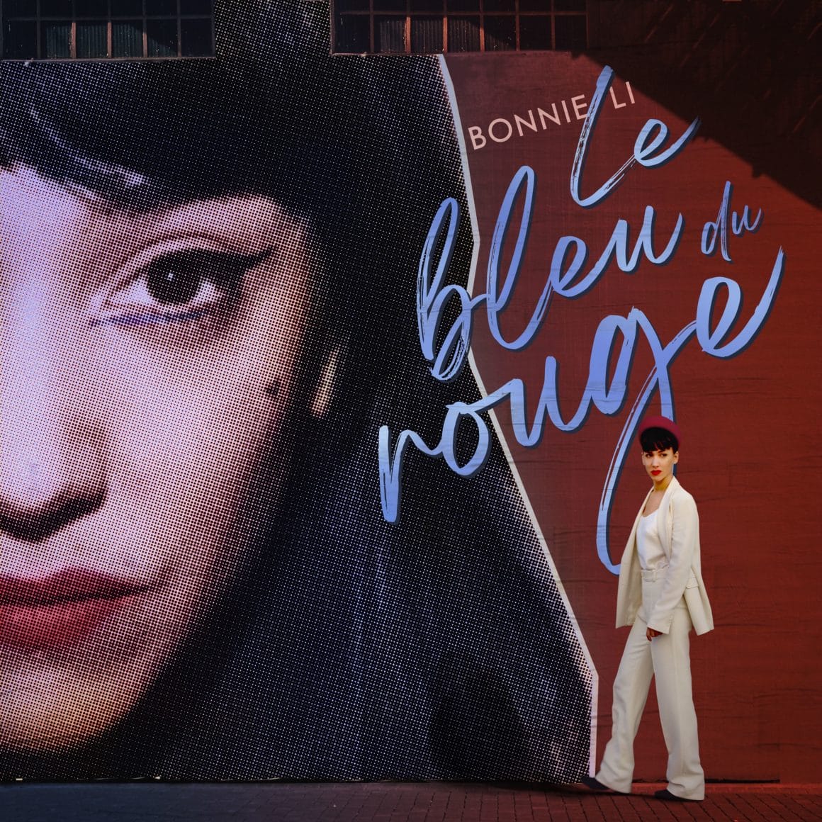 Bonnie Li se trouve face à un mur sur lequel se trouve une photo de son visage et le titre de son nouvel album. 