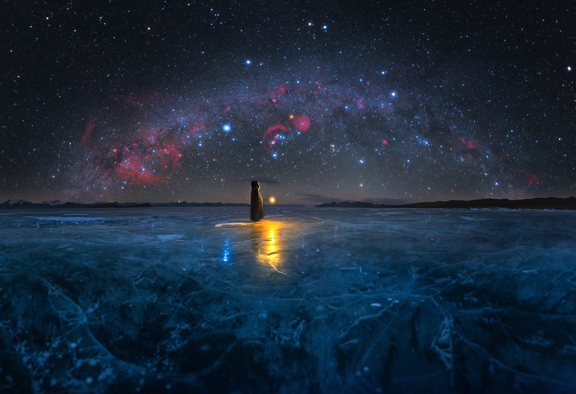 Photographie d'un lac gelé et de la voie lactée avec un personnage lumineux au centre