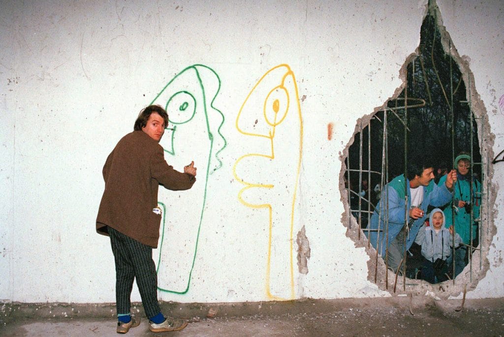 Thierry Noir devant le mur de Berlin dessinant