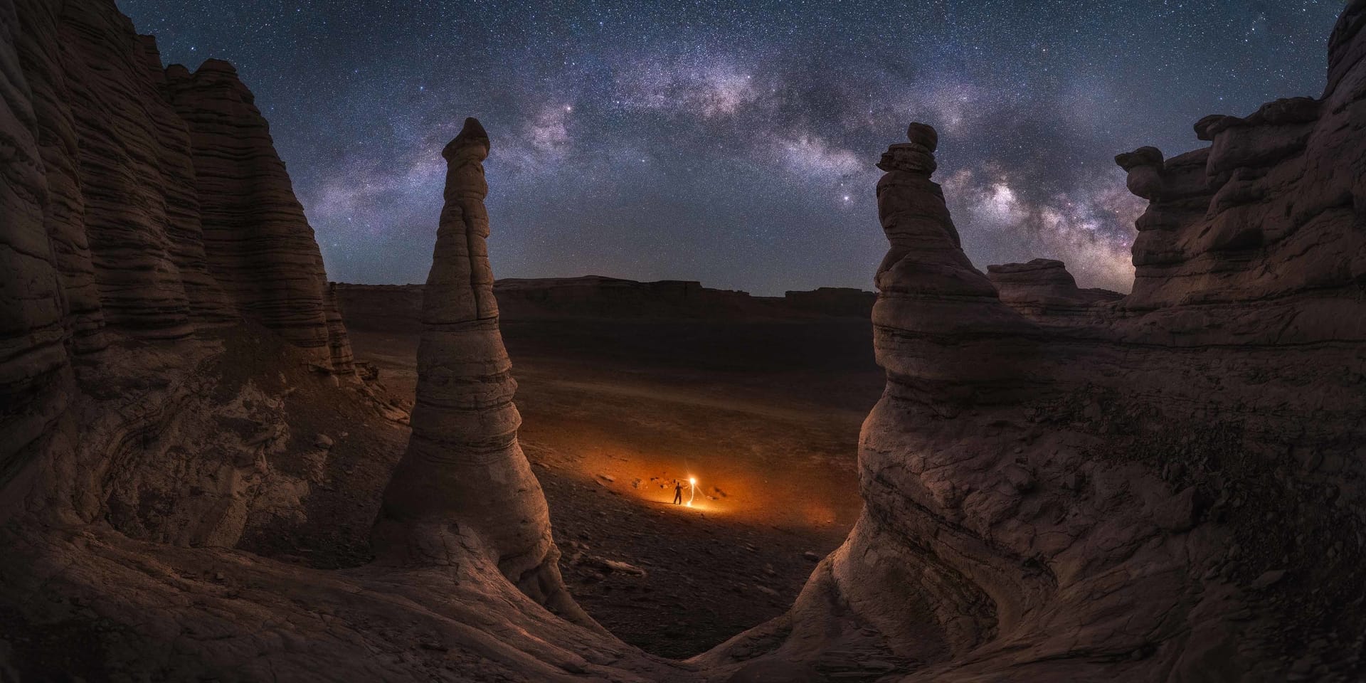Photo d'un désert avec un homme qui illumine le centre de la photo avec des flammes
