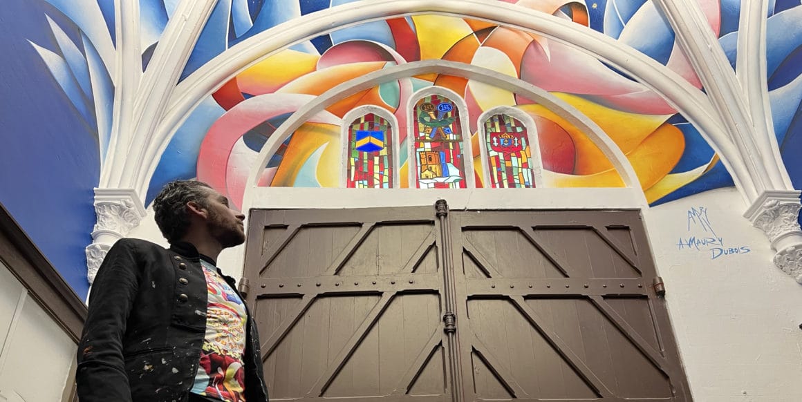Amaury Dubois devant sa fresque colorée de l'église Saint-Pierre de Calais
