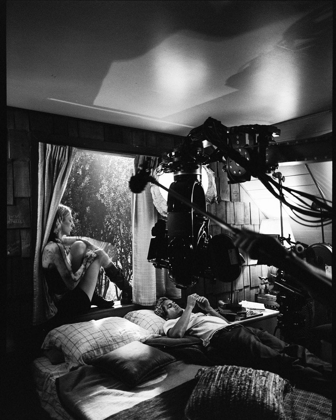 Backstages de la série où l'on voit la caméra, Hunter Shafer sur une fenêtre et Dominic Fike sur un lit. La photo est en noir et blanc