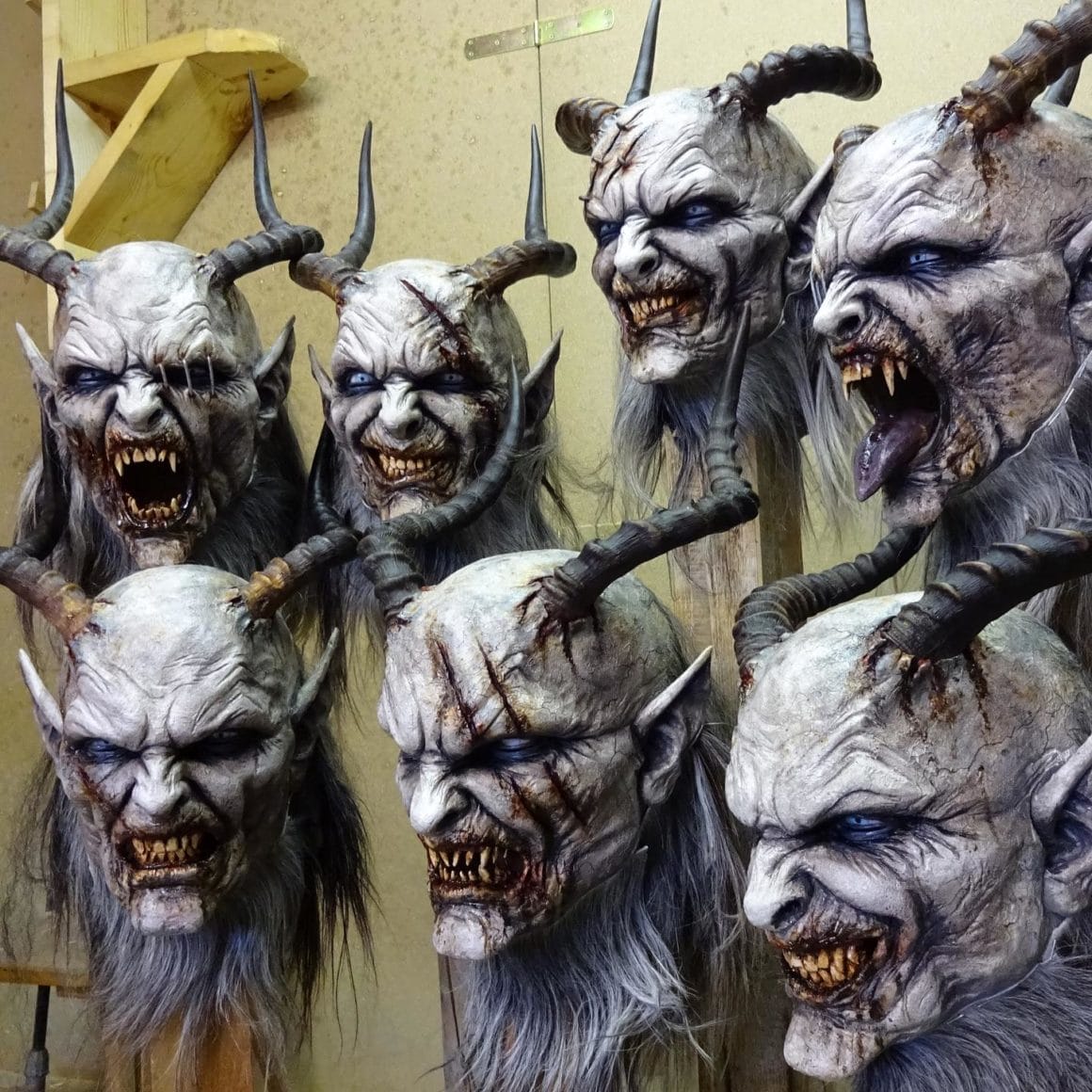 Exposition de masques créés par Stefan Koidl. Ils représentent des monstres aux grandes cornes, aux bouches badigeonnées de sang et aux dents jaunes.