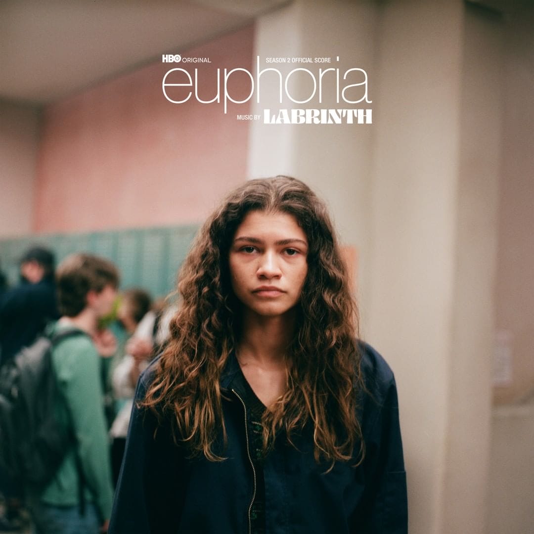 Affiche de la série Euphoria Zendaya se tient devant la caméra dans un couloir de lycée le visage sans émotion.