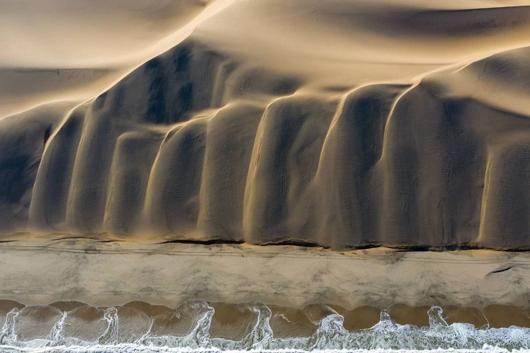 Photo d'une montagne de sable devant la mer étrangement symétrique