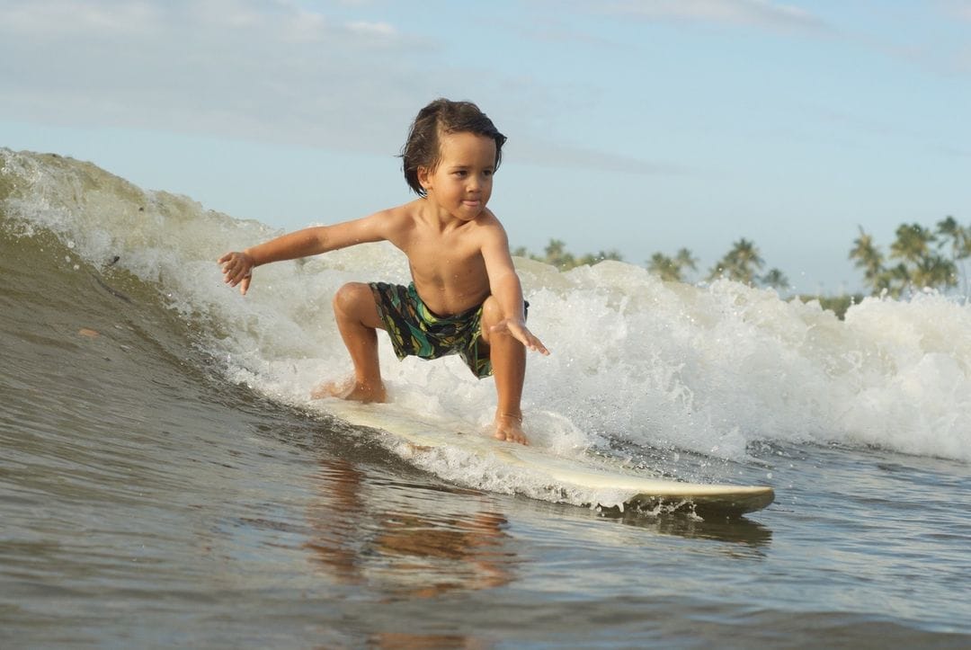 Une petit garçon sur très bien une vague.