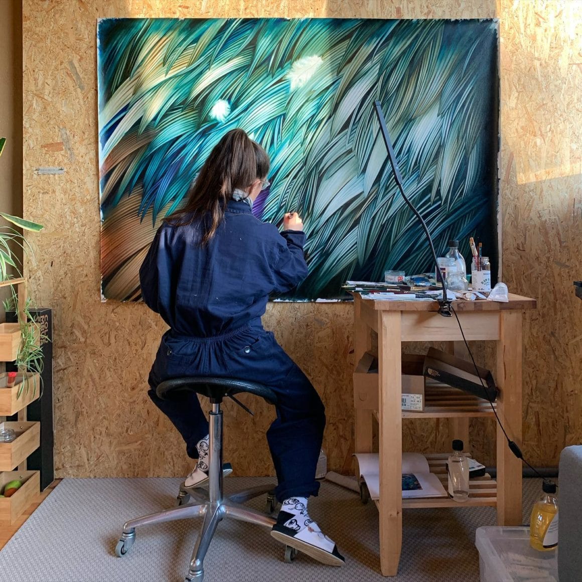 Adèle is in full creation in her studio.  She is painting green, blue and orange feathers