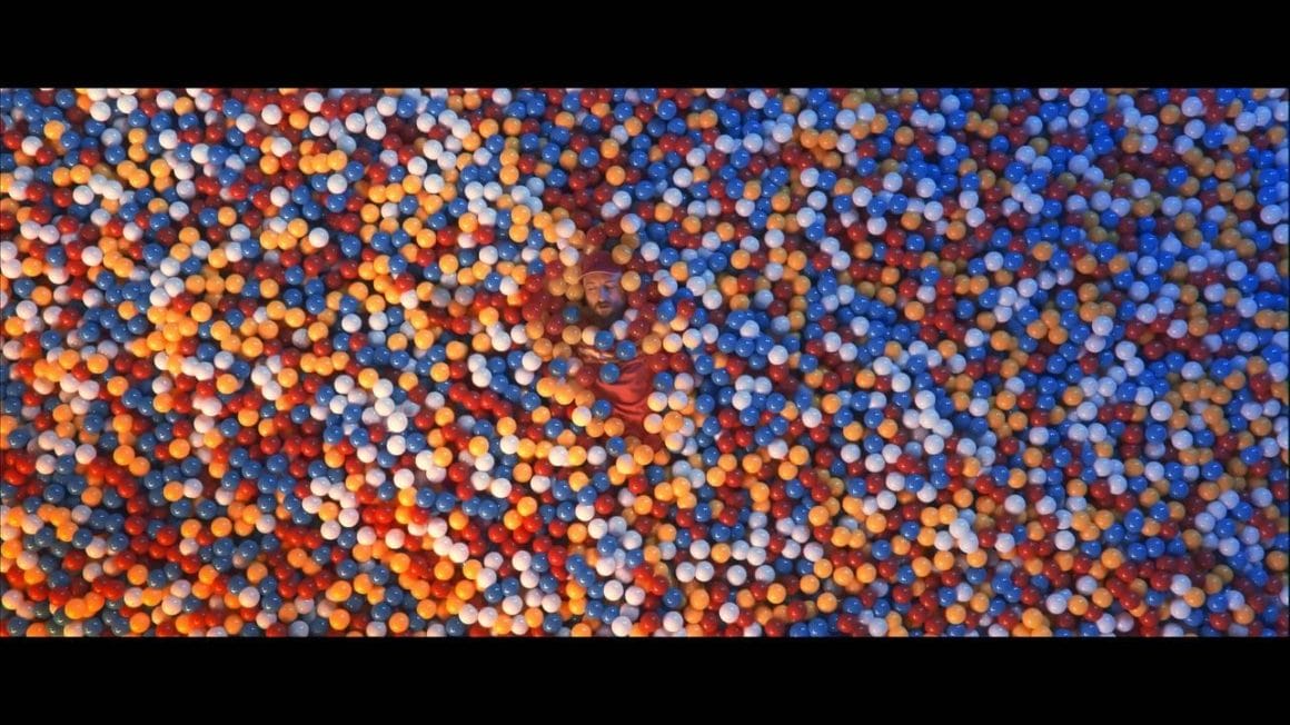 L'artiste Mcbaise est allongé dans une immense piscine à boules multicolores 
