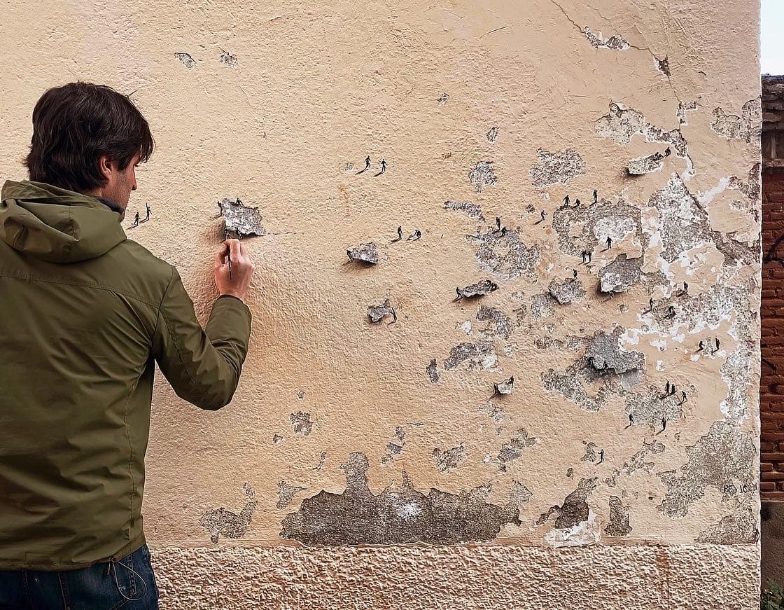 Pejac peint des petits bonhommes donnant l'illusion qu'ils tirent les morceaux d'un mur écaillé 